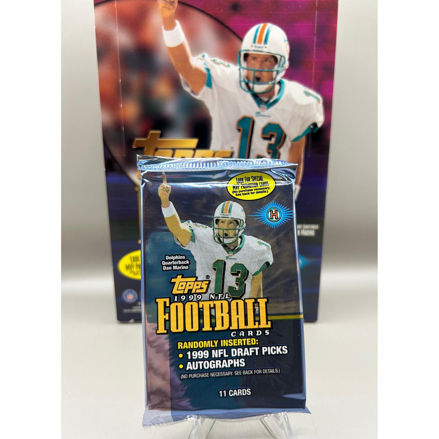 Sealed 1999 Topps NFL Football trading card pack featuring Dan Marino on the wrapper. Includes 11 cards with chance for autographs and draft picks.