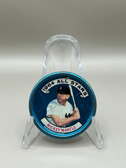 Front view of a 1964 Topps Mickey Mantle collectible coin featuring a portrait of the baseball legend, marked '1964 All-Stars,' displayed on a stand